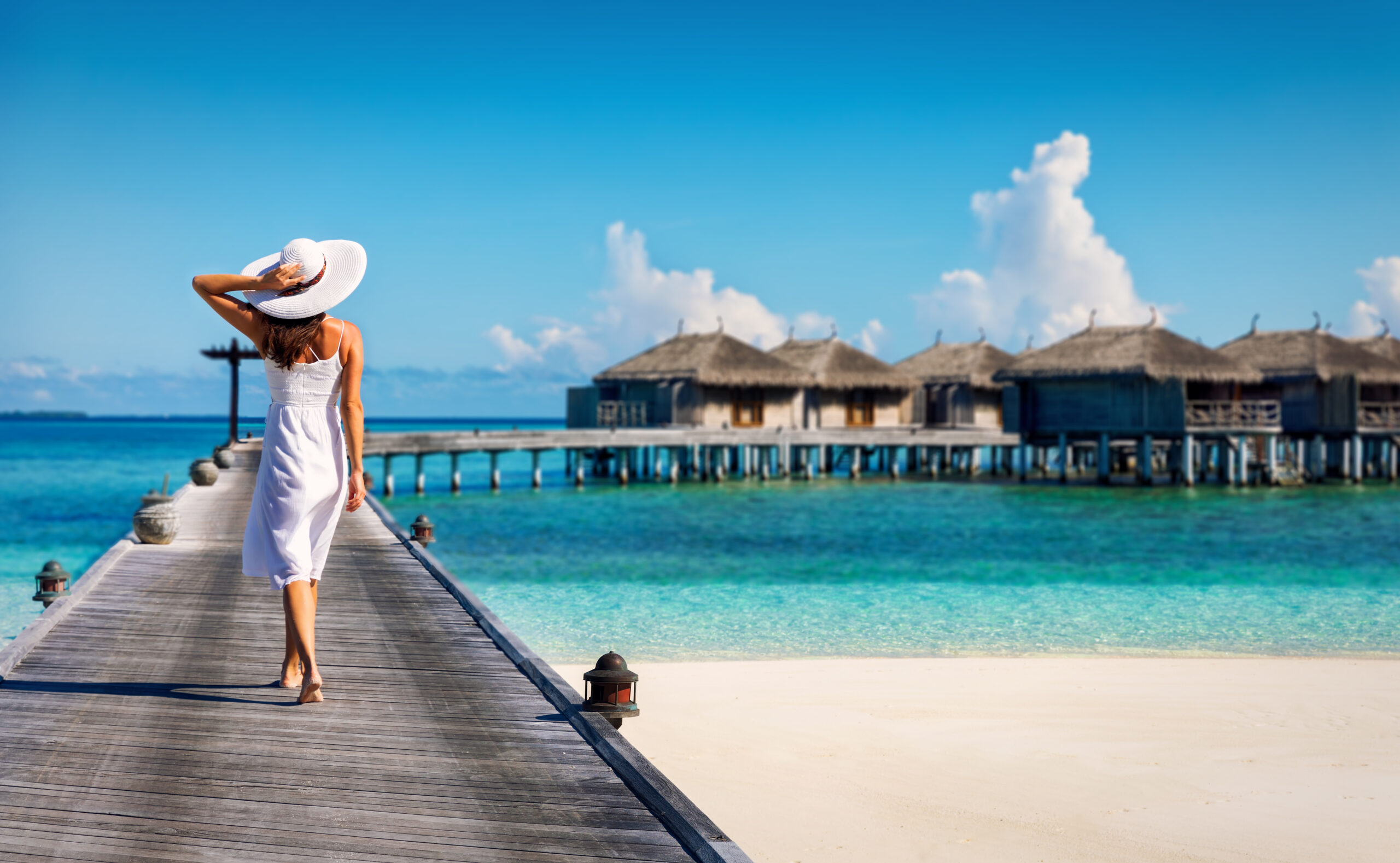 Woman in white walking along beach dock